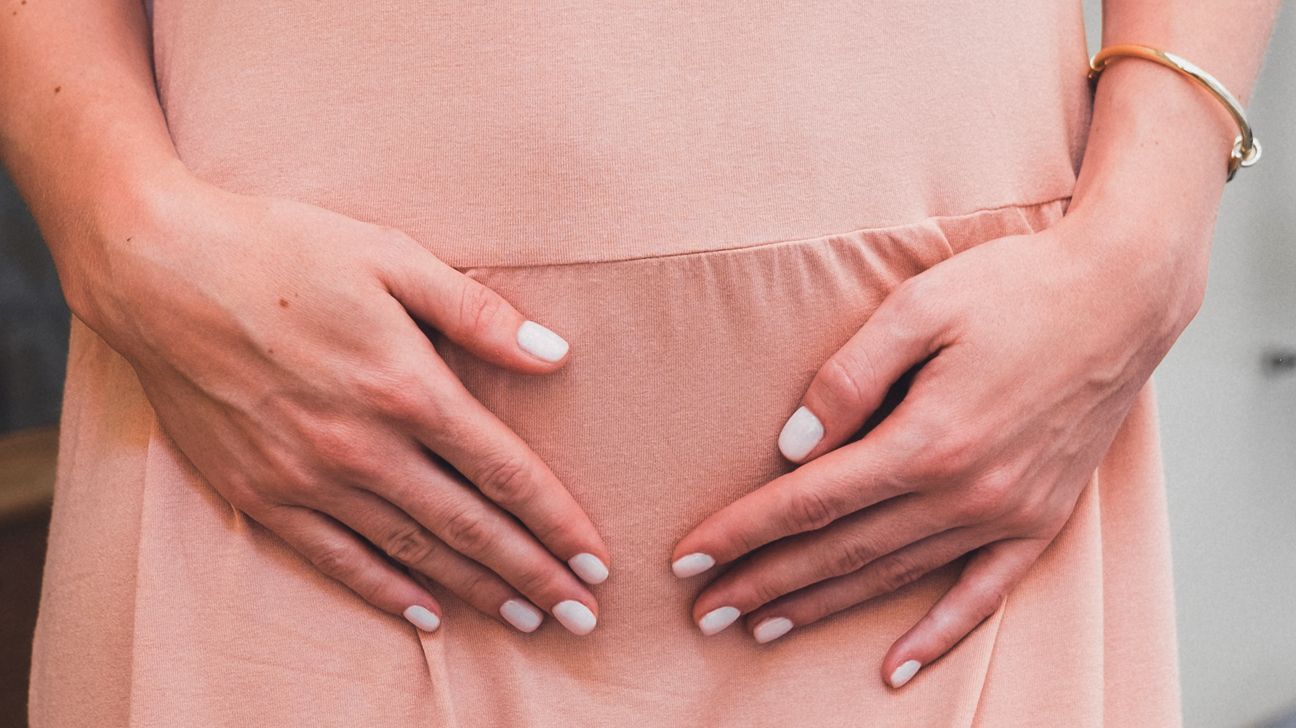 Person with their hands placed on their lower abdomen.