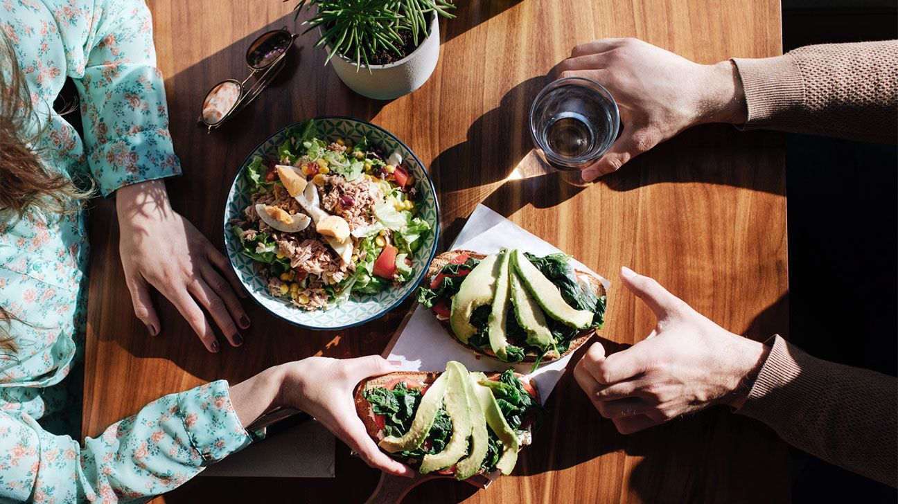 A table with healthy foods like chicken salad and avocado toast